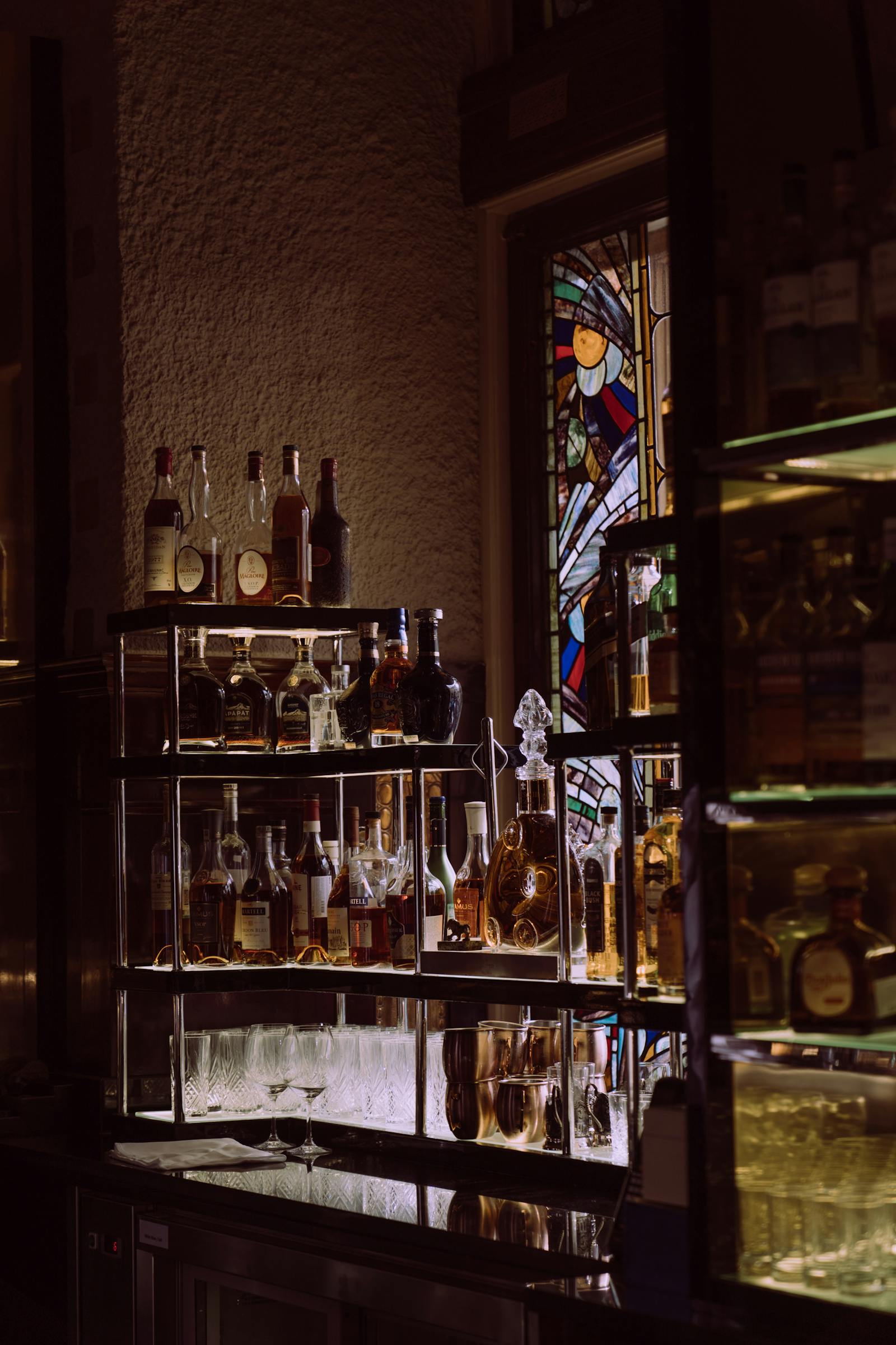 Bar feutré avec bouteilles éclairées et tabourets en velours