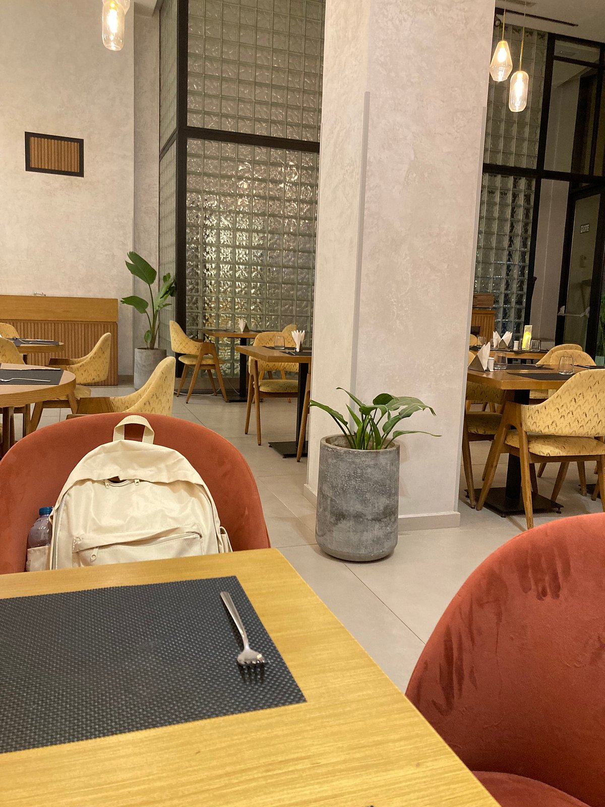 Salle de restaurant Nola avec tables dressées, murs ambrés et lumière chaude